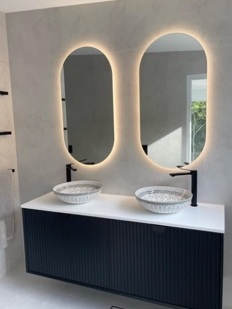 Bathroom shown on Torpedo’s Instagram, with twin illuminated mirrors and a dark vanity
