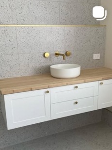 Timber-top vanity with white vessel basin and brass tapware